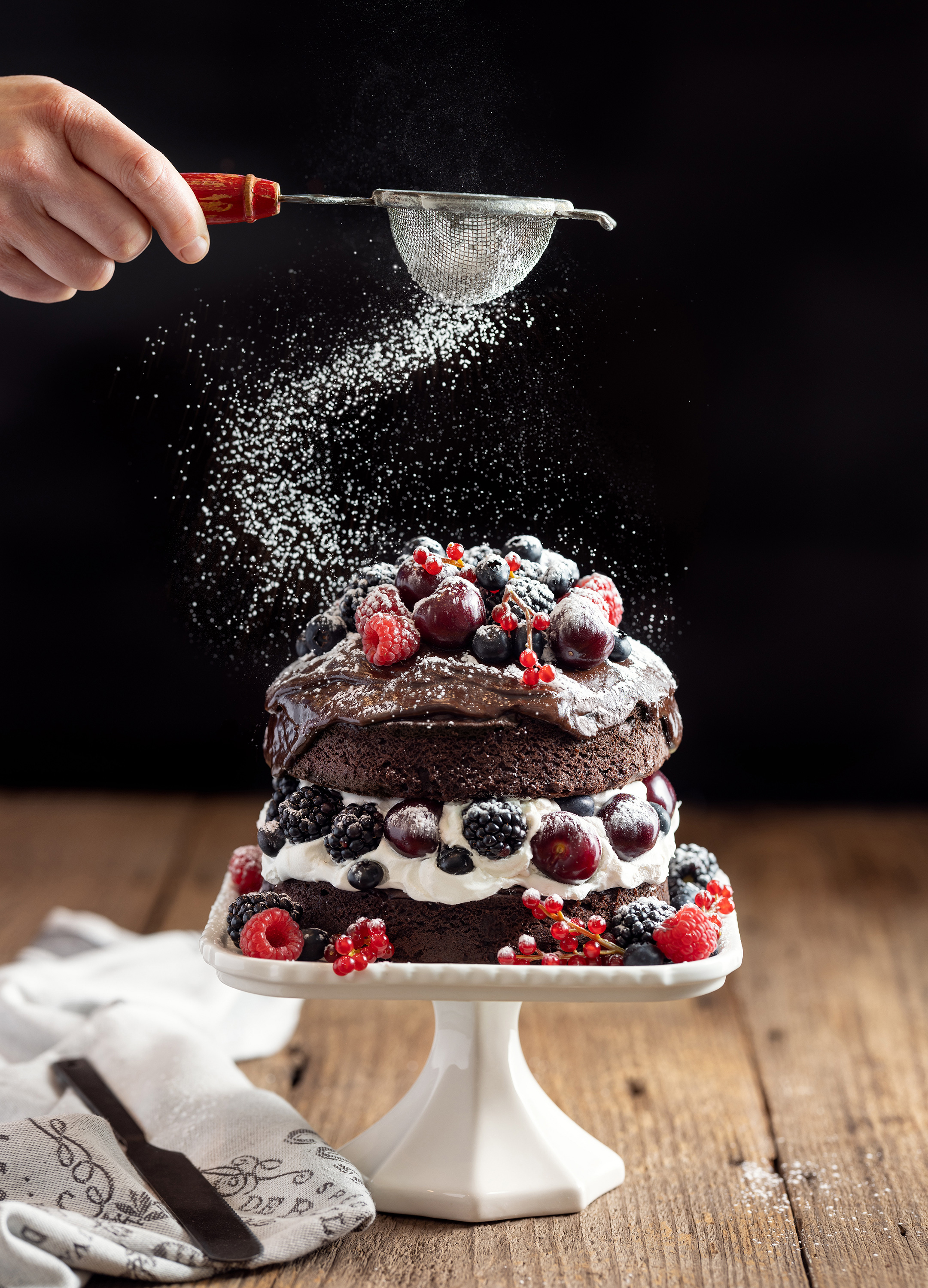 chocolate cake gateau with cherries blueberries and raspberries sprinkled with powdered sugar alyssa wernick food stylist styling dallas tx
